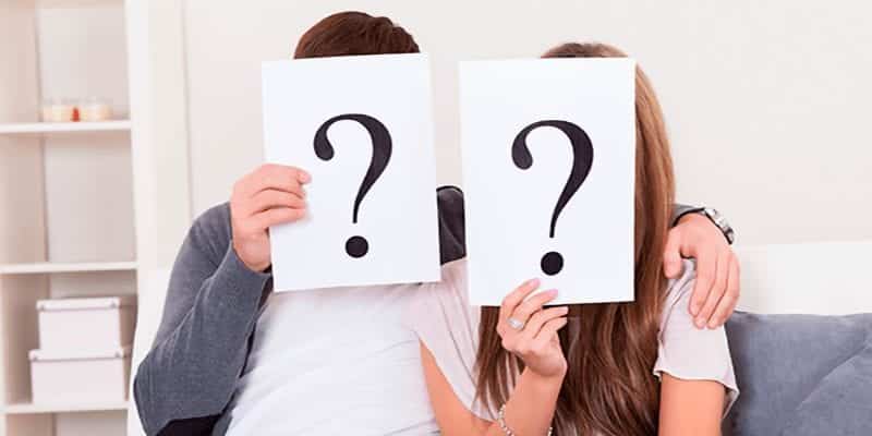 Couple on Couch With Question Marks In Front of Faces